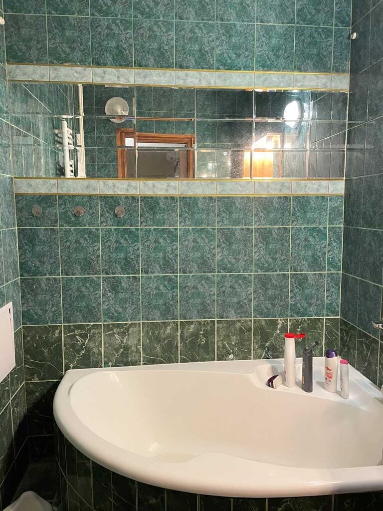 Fürdőszoba sarokkáddal és tükörburkolattal