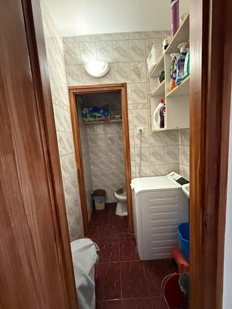 Fürdőszoba mosógéppel és fali polcokkal