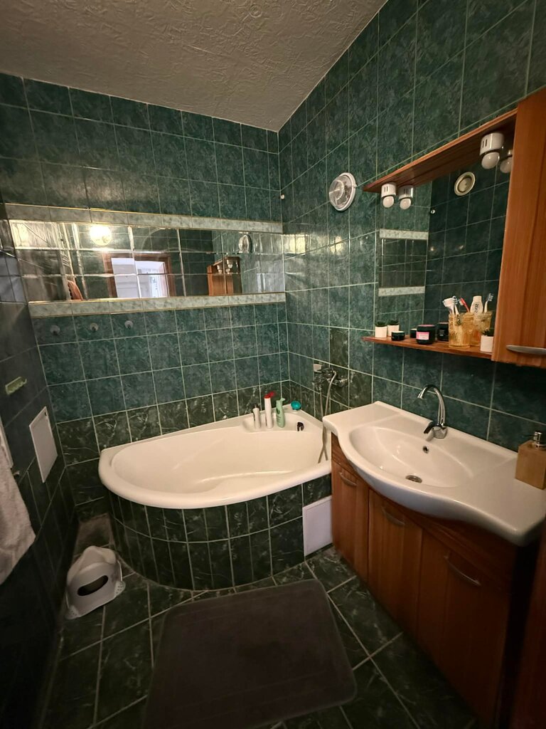 Fürdőszoba sötétzöld csempével és sarokkáddal